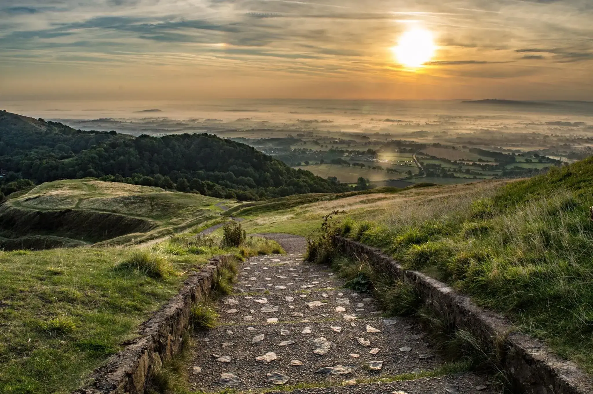 A path leading towards a serene horizon at sunrise.