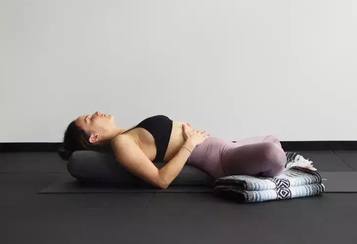 Woman relaxing in a Restorative Yin pose with props.